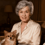 Ingrid van Bergen sitzt im hohen Alter friedlich in ihrem Wohnzimmer, begleitet von ihren zwei Hunden.