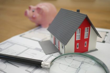 white and red wooden house beside grey framed magnifying glass
